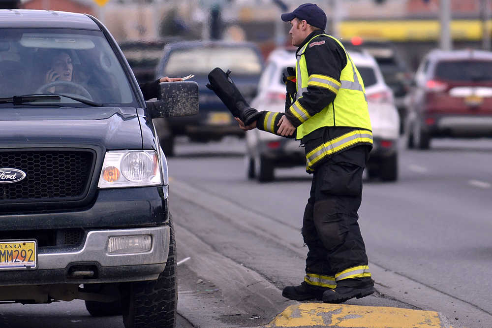 Photo by Rashah McChesney/Peninsula Clarion Kenai firefighter Dustin Voss takes money from a woman at a traffic light Friday October 17, 2014 in Kenai, Alaska. Several off-duty firefighters held a fill-the-boot campaign to raise money for the Muscular Dystrophy Association.