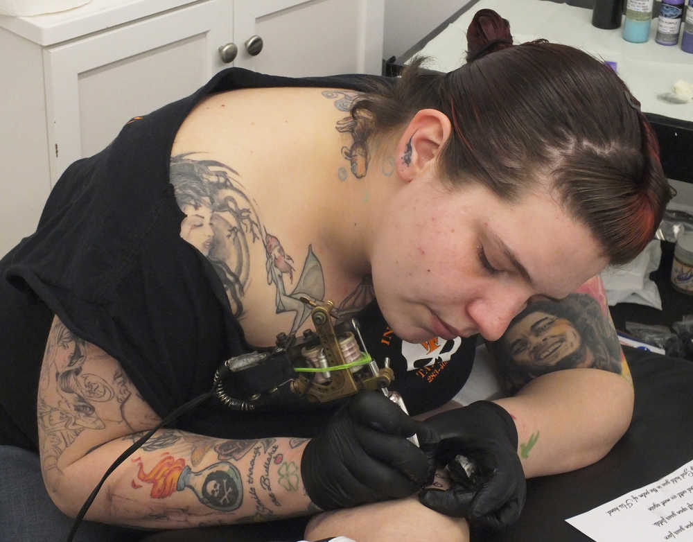 Ben Boettger/Peninsula Clarion Joe Hayes inks a tattoo on Ami Stowell's leg  at Ink Works Tattoo Studio in Kenai on Nov. 8.