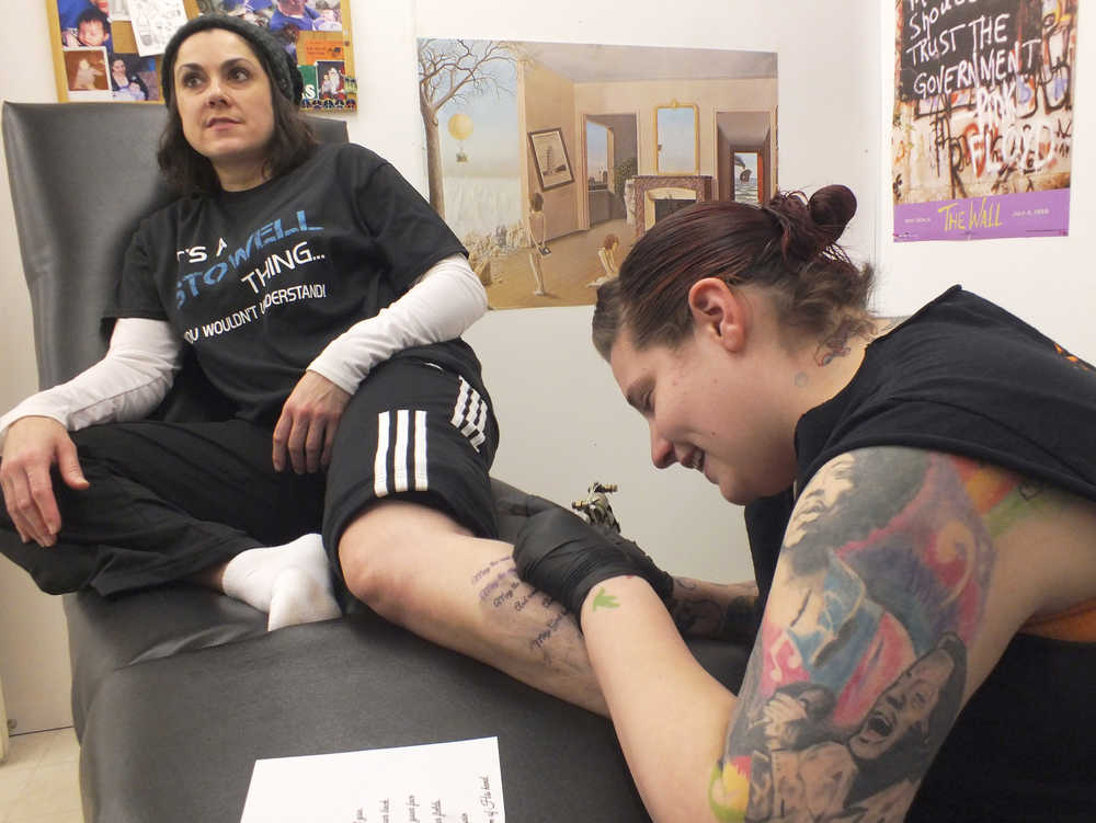 Ben Boettger/Peninsula Clarion Joe Hayes inks a tattoo on customer Ami Stowell's leg at Ink Works Tattoo Studio in Kenai on Nov. 8.