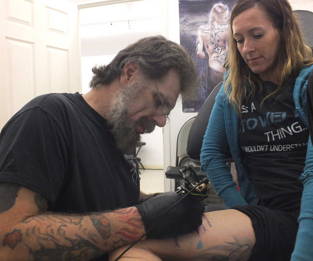 Ben Boettger/Peninsula Clarion Samantha Hayes inks a tattoo on customer Misty Stowell's leg at Ink Works Tattoo Studio in Kenai on Nov. 8..