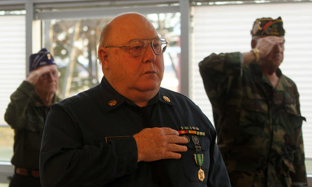 Photo by Dan Balmer/Peninsula Clarion Veterans salute during the singing of the National Anthem at the Veteran's Day ceremony Tuesday, Nov. 11, 2014 at the Soldotna Regional Sports Complex.