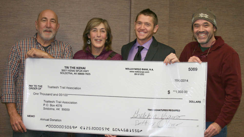 Tri the Kenai triathlon race director Tony Oliver and run/trail coordinator Kristine Moerlein present a donation of $1,000 to Tsalteshi Trails Association board member Mike Crawford and board president Dan Harbison. The donation came from funds raised by the triathlon, which utilizes Tsalteshi Trails for part of the race. (Submitted photo)