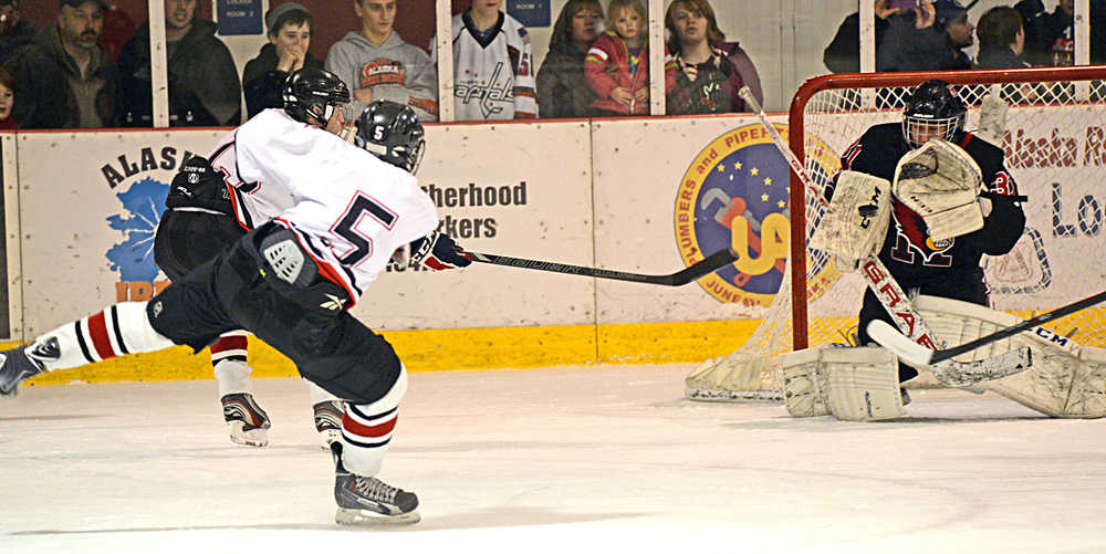 Juneau-Douglas junior forward Ryan Moritz (5) puts a shot on goal against Kenai senior goal tender Nate O'Lena (31) during Friday's 5-2 Crimson Bears win over the Kardinals at Treadwell Arena in Juneau.