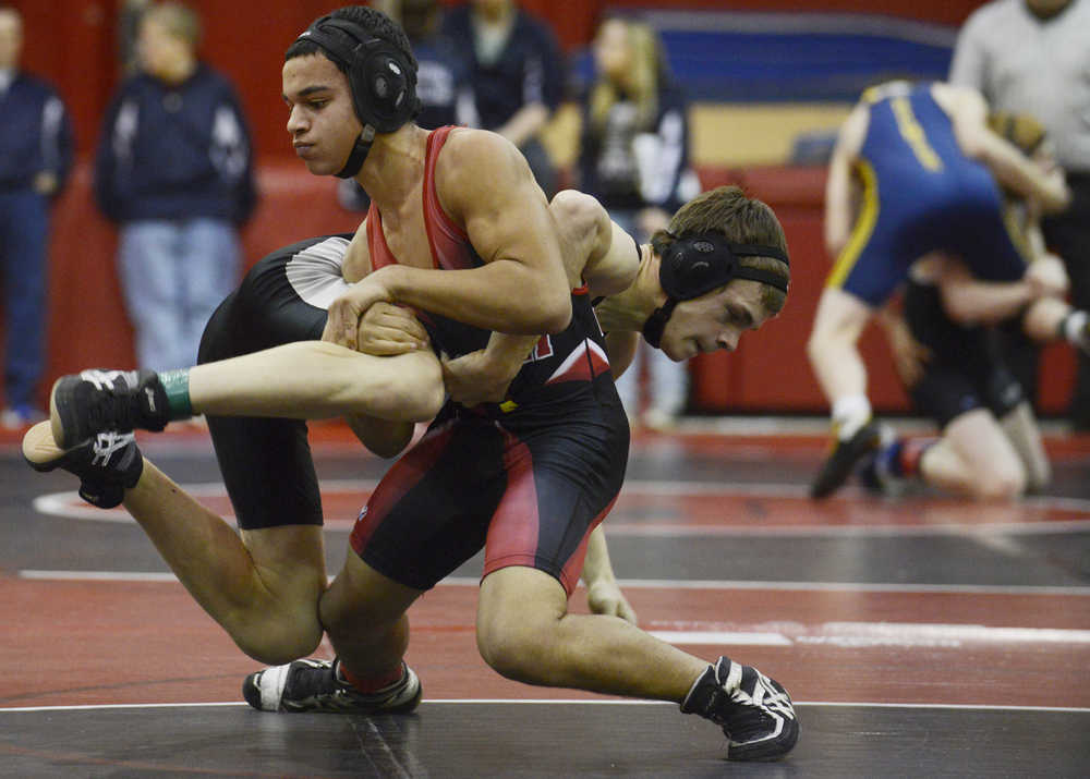 Photo by Kelly Sullivan/ Peninsula Clarion Kenai Central High School Kardinal Keyshawn McEnerney lifts Nikiski High-Middle School Bulldog Will Lynch in the 145-pound weight match during the Luke Spruill Memorial Wrestling Tournament Tuesday, November 25, 2014, at Kenai Central High School in Kenai, Alaska.