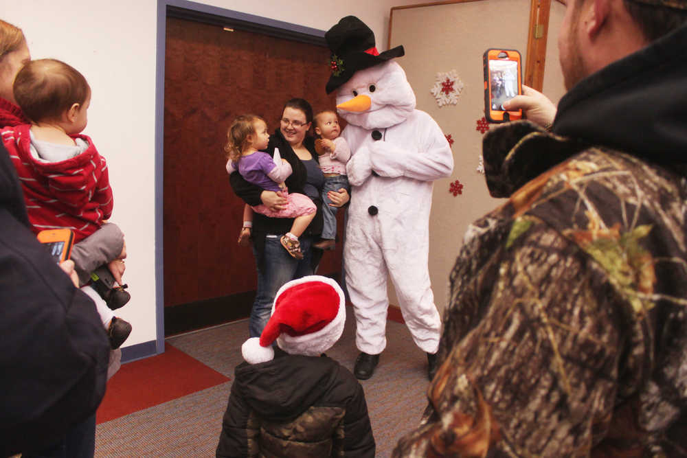 Photo by Kelly Sullivan/ Peninsula Clarion Avah, Kenzy and Alyssa Weeks pose for photos with Frosty the Snowman at  Christmas Comes to Kenai November 28, 2014, in at the Kenai Chamber of Commerce and Visitor Center in Kenai, Alaska. Ivan Weeks said it was the first year Avah Weeks would be seeing Santa Claus, but her sister Kenzey Weeks had before.