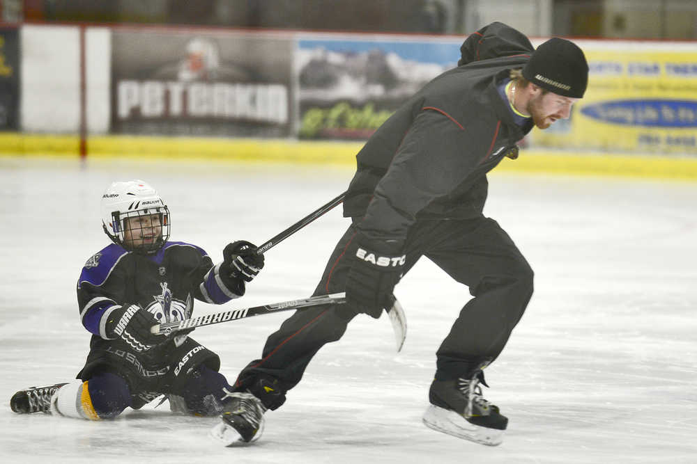 Photo by Rashah McChesney/Peninsula Clarion  Ryan Buchanan, 7, gets a tow from Soldotna Parks and Recreation employee Trevor Baldwin during a power hockey class on Tuesday Dec. 2, 2014 in Soldotna, Alaska. Buchanan was the only student who attended the class and got a private lesson for the evening.