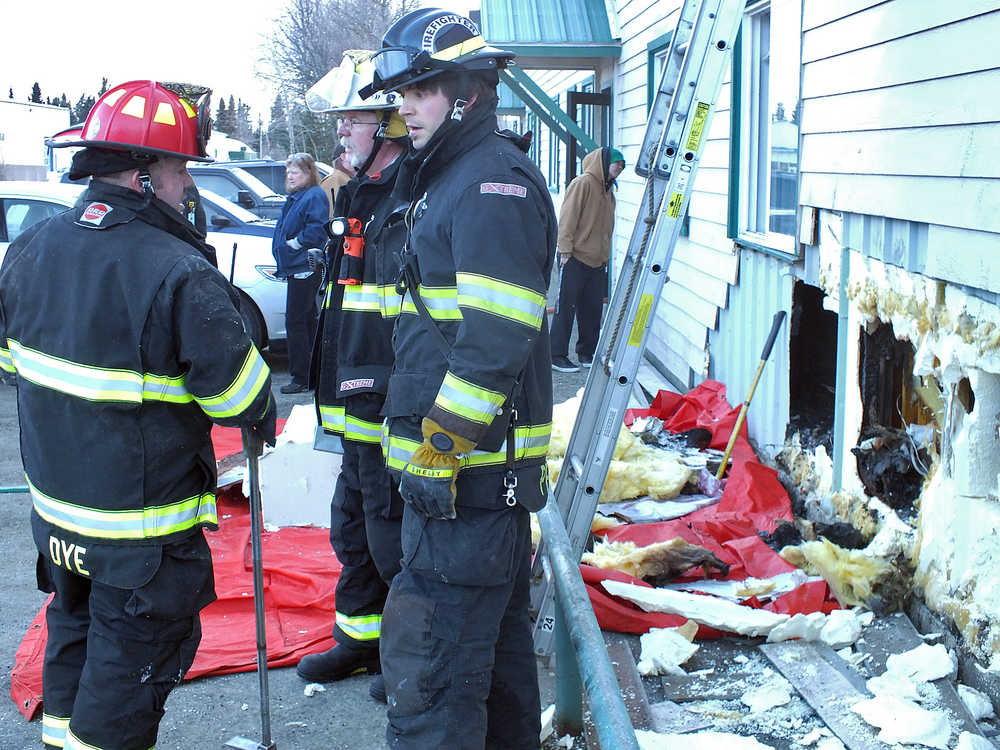 Ben Boettger/Peninsula Clarion Kenai Fire Department Capt. James Dye talks to Kenai Firefighter Zach Pettit on Wednesday Dec. 10, 2014 outside of the Kenaitze Indian Tribe's administration building on Willow Street in Kenai. Firefighters responded to reports of smoke at about noon and worked to discover an ignition point in a portion of the building.