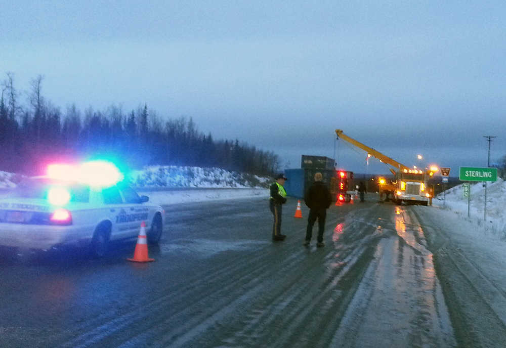 Photo by Dan Balmer/Peninsula Clarion Alaska State Trooper John King talks to a motorist after a truck trailer lost control and overturned on the ice at Mile 80 of the Sterling Highway Monday. The crane tow truck blocked traffic for 45-minutes before one lane opened up. The scene was cleared by 11 a.m.