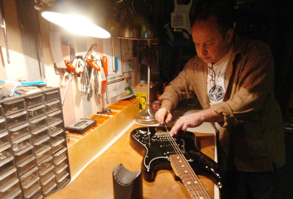 Photo by Kelly Sullivan/ Peninsula Clarion Dustin Aaronson, owner of Old Town Music, works on adjusting the intonation on an American made electric guitar Tuesday, Dec. 16, 2014, in Kenai, Alaska. Intonation affects sound quality throughout the entire instrument, and while the technique is generally formulaic, sometimes rules are broken to ensure individual instruments have been properly tuned, Aaronson said.