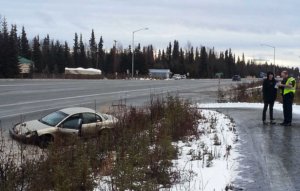 Photo by Dan Balmer/Peninsula Clarion Kenai police Sgt. Jay Sjogren talks with an 18-year old man Tuesday, Dec. 16, 2014 after a single-vehicle rollover at about 10:45 a.m. on the Kenai Spur Highway. The driver of the tan Saturn sedan was traveling toward Soldotna when he hit a patch of ice on a turn, rolled over once and came to a stop in the ditch. The driver was not injured and the vehicle was towed from the scene.