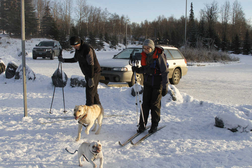 In this photo taken on Dec. 18, 2014, Dan and Terry Goodwin, from left to right, prepare for an afternoon of cross-country skiing as snow-making machines churn snow at the city's largest park in Anchorage, Alaska. A spate of weird weather lingers in Anchorage, which is almost 2 feet behind typical snowfall totals for December. (AP Photo/Mark Thiessen)