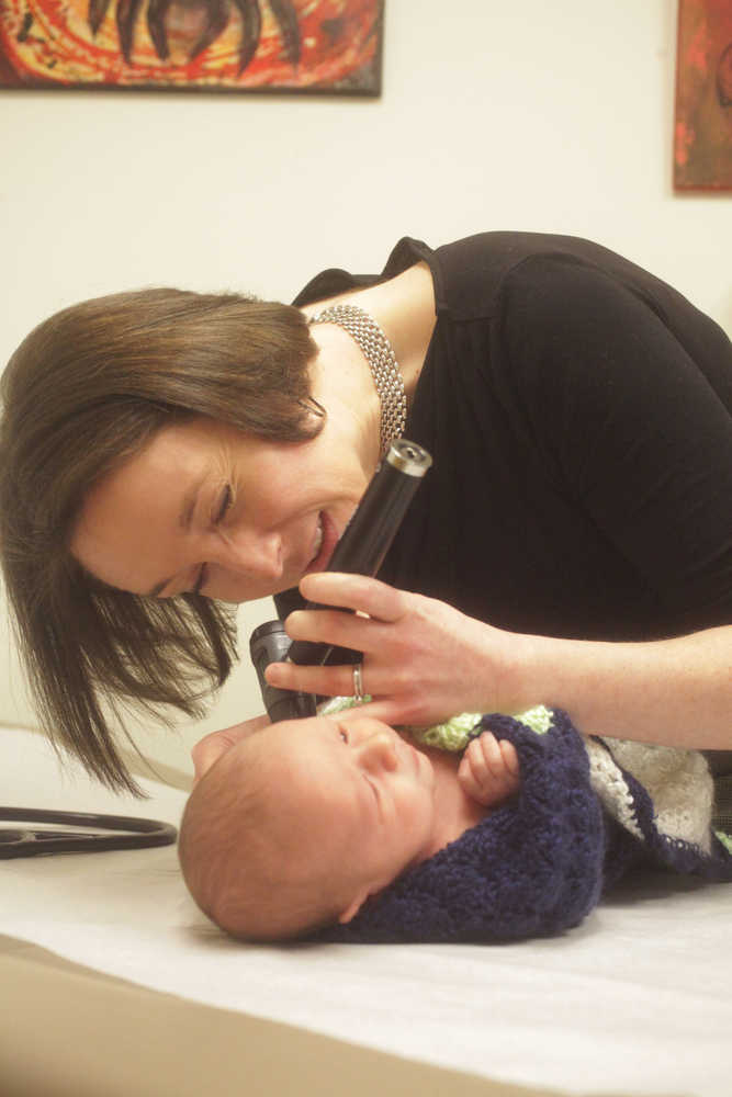 Photo by Kelly Sullivan/ Peninsula Clarion Kristen Lee, owner of Upstream Family Medicine, gives four-week-old Baylor Sansotta a well child check-up Monday, Dec. 22, 2014 in Soldotna, Alaska. His mother Erin Sansotta watches in the corner as her son whines about how cold the otoscope is that Lee uses to check his ears. said care provider and owner Kristen Lee, who runs the practice with Tara Lathrup