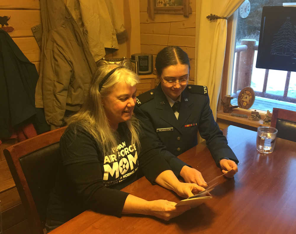 By IAN FOLEY/ Peninsula Clarion Betsy Laws and her daughter Kiowa Richardson look through pictures of their old cabin on December 22, 2014 in Soldotna.