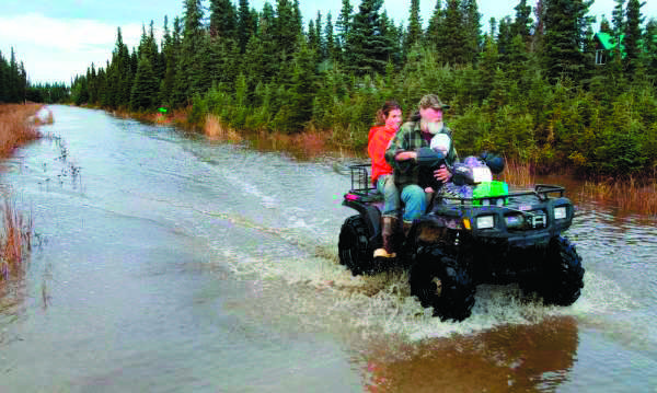 Clarion file photo Paul Vass and Julie Wendt drive down Bore Tide Drive during an October 2013 tour of the Kalifornsky area subdivision in which they live and raise livestock on a small farm. The couple suffered and estimated $30,000 in damage to their livestock and home during the month's long groundwater-flooding event that peaked from weekend rains