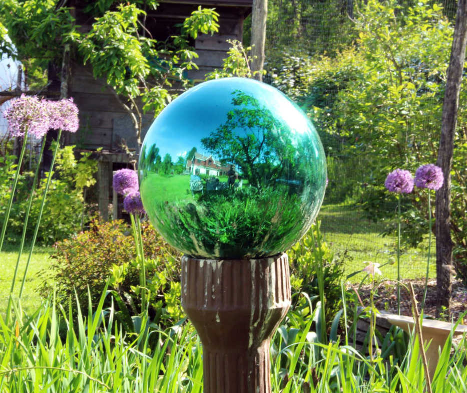 In this undated photo, a green-tinted gazing globe visually takes in all of last summer's garden in New Paltz, New York. These mirrored glass ornaments fell out of favor about 50 years ago, but are making a comeback, seen by some as attractive ornaments and by others as kitsch. (AP Photo/Lee Reich)