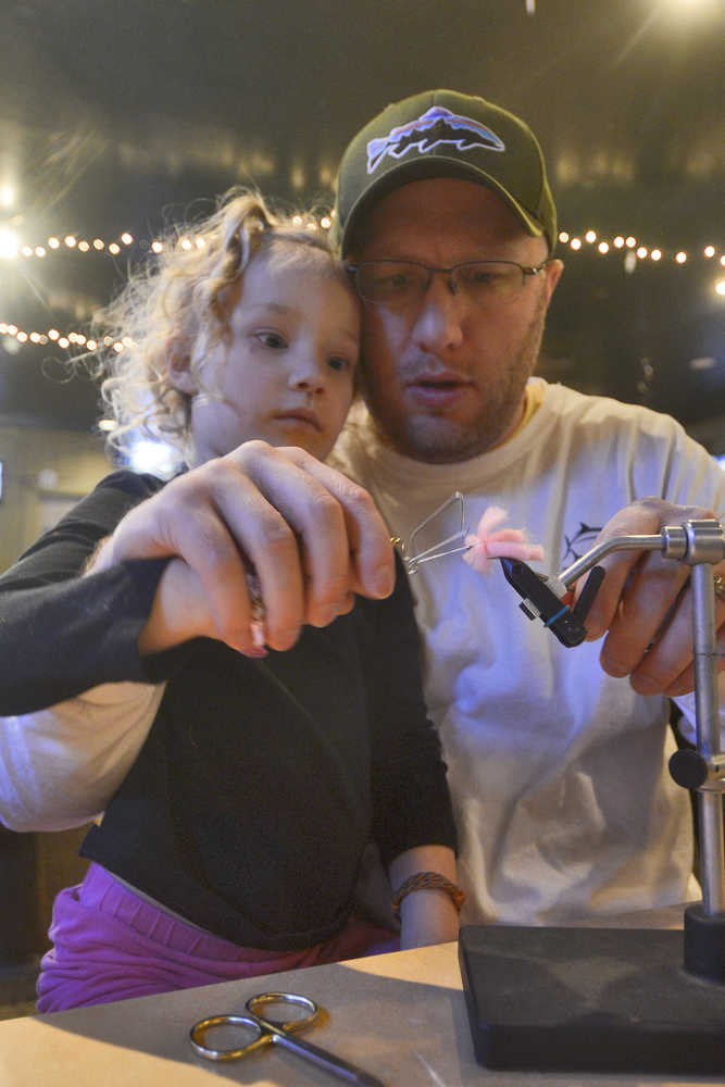 Photo by Rashah McChesney/Peninsula Clarion  Zaydri Pond, 3, helps her dad Shane Pond trim a bit of yarn tied to a fishing hook during a fly-tying class on Tuesday Jan. 6, 2014 at the Main Street Tap & Grill in Kenai, Alaska.