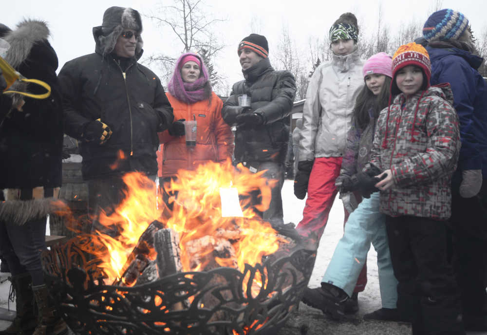 Ben Boettger/Peninsula Clarion A group gathers around a fire during the Frozen River Festival at Soldotna Creek Park on Saturday, Feb. 7.