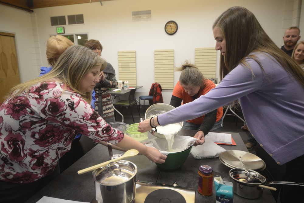 Photo by Kelly Sullivan/ Peninsula Clarion Beth Lyons and Anne McCabe help Amy Lou Pascucci during one of the beginning steps of making Paneer Tuesday, Feb. 10, 2015, at the Kenai Community Library in Kenai, Alaska. Lyons said, in the past, she has visisted the library mainly so she and her children could check out reading materials. More recently she, and she believes the wider community, come for classes such as Pascucci's cheese-making workshop, and as a place to congregate.