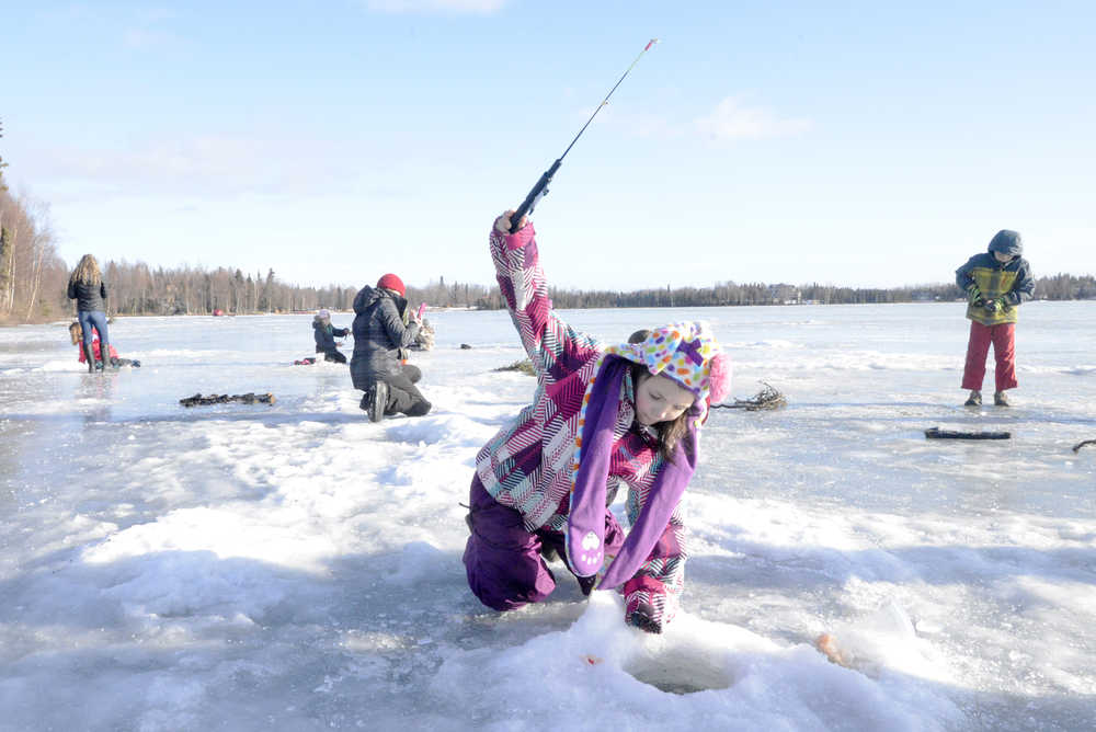 Ben Boettger/Peninsula Clarion Molly McMillan (right) jigs a lure while her father Sandy McMillan (seated) uses a fish camera during the Alaska Department of Fish and Game's ice fishing event at Sports Lake on Wednesday, February 18.
