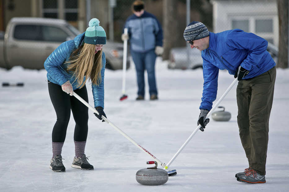 ADVANCE FOR USE MONDAY, FEB. 16 - In this photo taken Jan. 17, 2015, curling enthusiasts sweep the ice behind a stone during a curling clinic hosted by the Bozeman Parks and Recreation Department at Southside Park in Bozeman, Mont.. Participants learn the basics of the game and help raise interest in the sport. (AP Photo/Bozeman Daily Chronicle, Adrian Sanchez-Gonzalez)