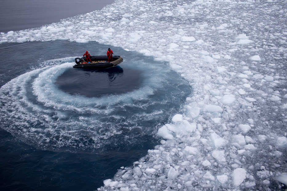 In this Jan. 22, 2015 photo, Chilean Navy officers push away ice by moving their boat in circles as they approach the Aquiles navy ship where they will pick up international scientists and take them to Chile's scientific Station Bernardo O'Higgins in Antarctica. While tourists come to Antarctica for its beauty and remoteness, scientists are all business. What they find could affect the lives of people thousands of miles away. (AP Photo/Natacha Pisarenko)