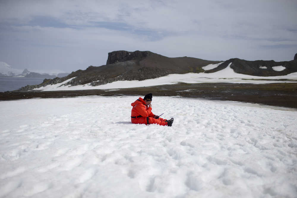 In this Jan. 24, 2015 photo, a worker from the Chile's Antarctic Institute sits on the snow on Robert Island, part of the South Shetland Islands archipelago in Antarctica. NASA uses the remoteness of Antarctic to study what people would have to go through if they visited Mars. The dry air also makes it perfect for astronomers to peer deep into space and into the past. (AP Photo/Natacha Pisarenko)