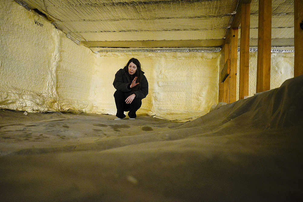 Photo by Rashah McChesney/Peninsula Clarion Debbie Brown, of Soldotna, squats in her damp crawl space on Silverweed Street where she said water has been seeping underneath the plastic on Saturday Feb. 28, 2015 in Soldotna, Alaska.