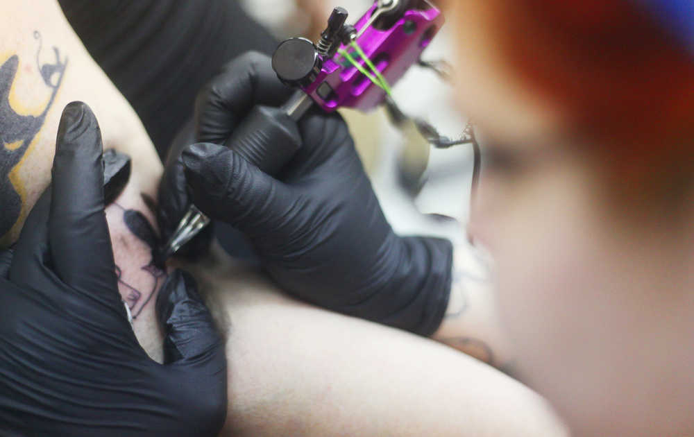 Photo by Kelly Sullivan/ Peninsula Clarion Lori Salyers, who is getting a black and white image of a cat sitting beside a tombstone just below her shoulder, said the tattoo was inspired by her favorite holiday, which is Halloween, Saturday, March 14, 2015, at Ink Works in Kenai, Alaska.