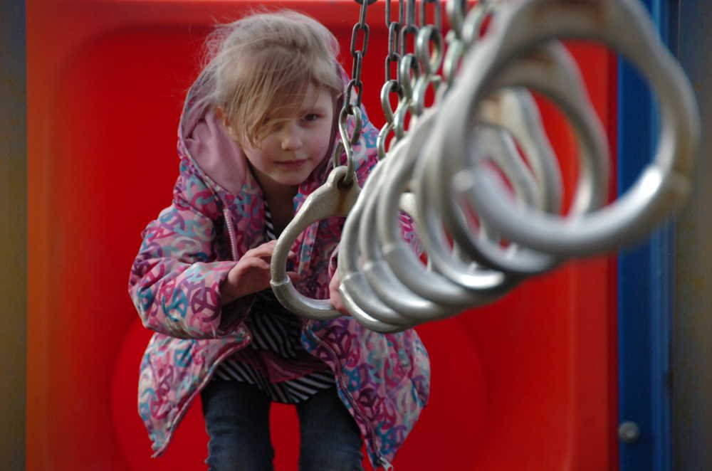 Photo by Kelly Sullivan/ Peninsula Clarion Harmonyrain Enders gets ready to take a swing on the playset rings at Kenai Municipal Park after school Monday, March 30, 2015 in Kenai, Alaska.