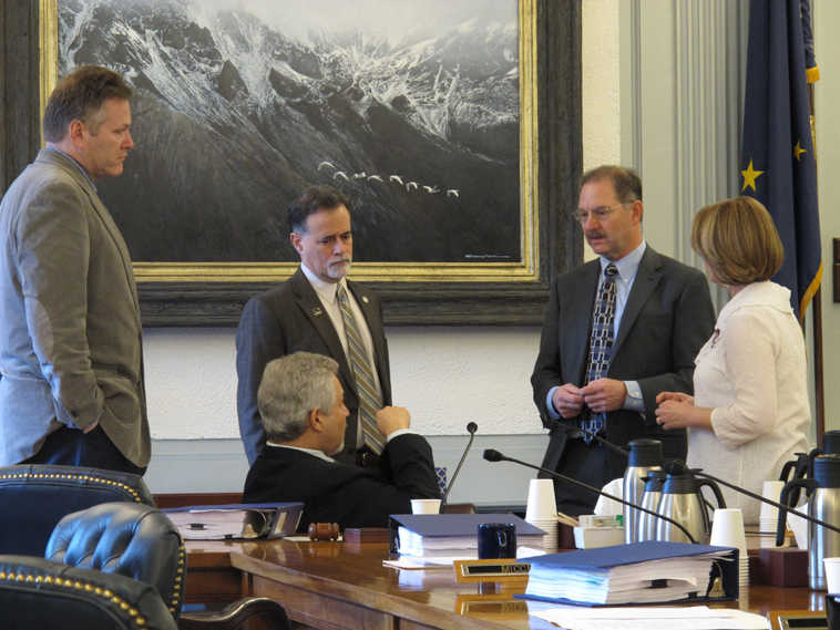 Members of the Senate Finance Committee speak with Legislative Finance Division director David Teal, second from right, during a break in a hearing on Wednesday, April 1, 2015, in Juneau, Alaska. Shown standing are, from left, Sens. Mike Dunleavy and Peter Micciche, Teal and Sen. Anna MacKinnon. Seated is Sen. Pete Kelly. (AP Photo/Becky Bohrer)
