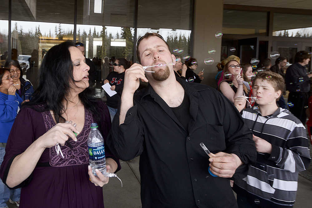 Photo by Rashah McChesney/Peninsula Clarion Lisa Hundley and Paul Karella blow bubbles on Saturday April 4, 2015 during a memorial for Hundley's daughter-in-law Rebecca Adams and grandchildren Michelle Hundley and Jaracca Hundley who were found dead in a field near their home in Kenai, Alaska.