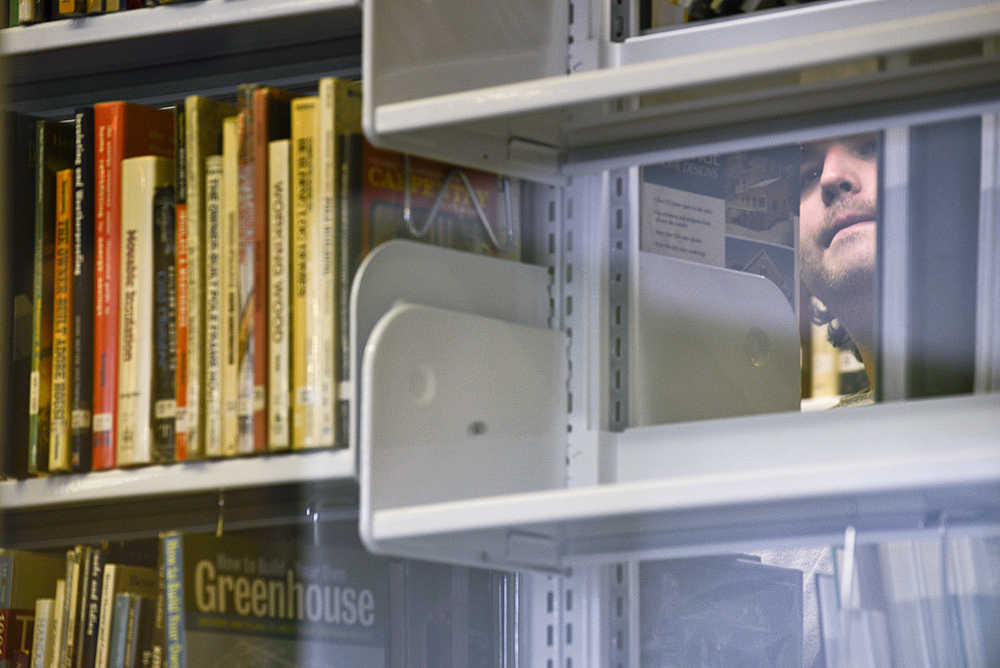 Photo by Rashah McChesney/Peninsula Clarion  Erik Hendrickson, of Nikiski, settles on a book about tiny houses on Wednesday April 8, 2015 at the Kenai Community Library in Kenai, Alaska.