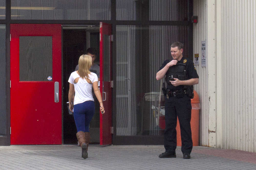 Photo by Rashah McChesney/Peninsula Clarion  An officer from the Kenai Police Department talks to a woman as she enters Kenai Central High School on Tuesday April 14, 2015 in Kenai, Alaska. Officers responded to the school after a student received a threatening text and the school was put into lockdown mode.