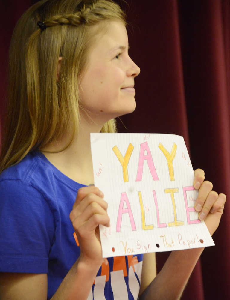 Photo by Kelly Sullivan/ Peninsula Clarion Kenai Central senior Allie Ostrander holds up a sign handmade by a friend for encouragement right before signing a National Letter of Intent to run at Idaho's Boise State University Wednesday, April 15, 2015, at Kenai Central High School in Kenai, Alaska.