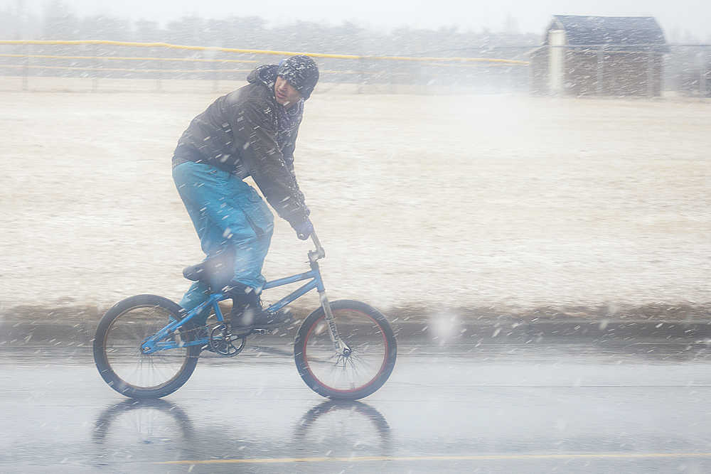 Photo by Rashah McChesney/Peninsula Clarion  A man rides his bicycle on the Main Street Loop on Thursday April 16, 2015 in Kenai, Alaska. It snowed for about an hour before the storm subsided.