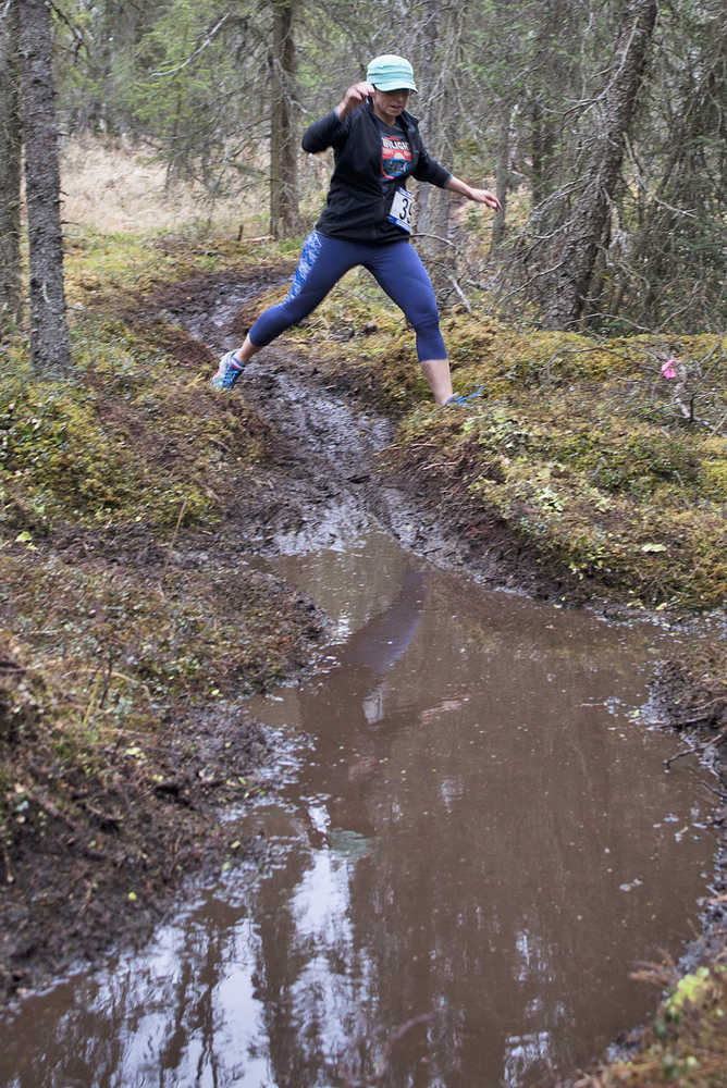 Photo by Rashah McChesney/Peninsula Clarion Patty Moran leaps from one side of a trail to the other during the Choose Your Weapon race on the Tsalteshi Trails Saturday April 18, 2015 in Soldotna, Alaska.