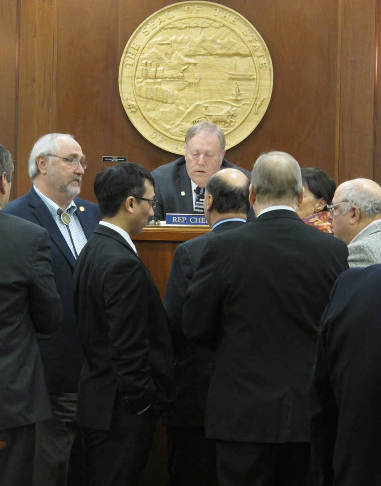 Republican and Democratic lawmakers gather in front of House Speaker Mike Chenault, center, following a parliamentary question on a proposed amendment to the capital budget on Monday, April 20, 2015, in Juneau, Alaska. (AP Photo/Becky Bohrer)