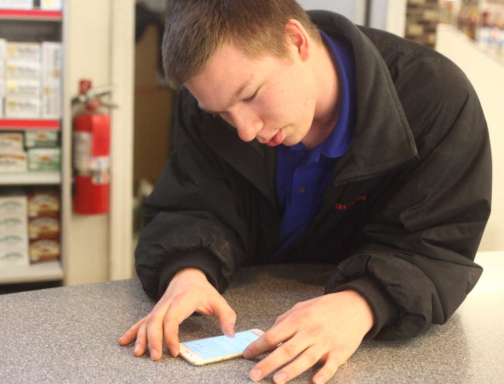 Photo by Kelly Sullivan/ Peninsula Clarion Isaiah Metcalf reads the email he has been waiting for for two days that confirms he is the winner of the Global Technical Service's $10,000 annual scholarship Saturday, April 25, 2015, at Country Foods IGA in Kenai, Alaska.