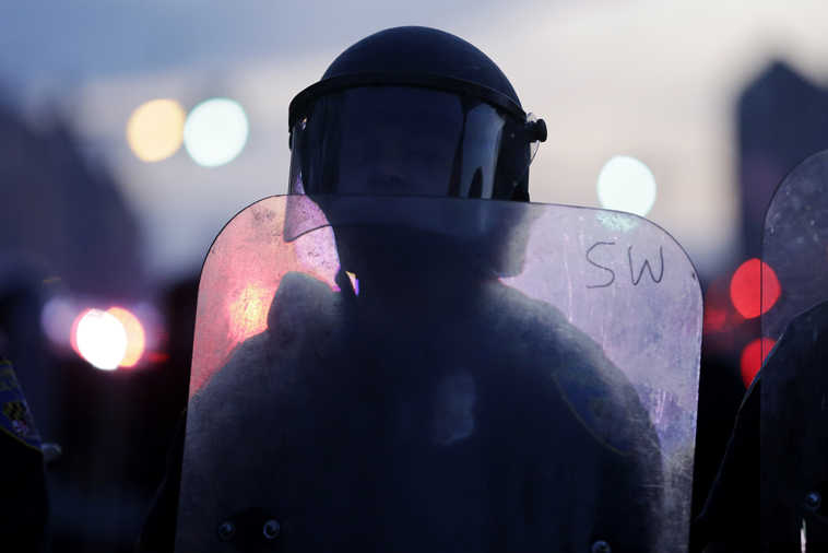 A police officer stands guard Monday, April 27, 2015, after rioters plunged part of Baltimore into chaos, torching a pharmacy, setting police cars ablaze and throwing bricks at officers.  (AP Photo/Matt Rourke)