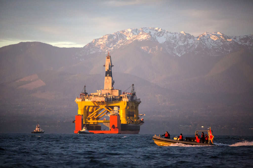 FILE - In this April 17, 2015 file photo, with the Olympic Mountains in the background, a small boat crosses in front of an oil drilling rig as it arrives in Port Angeles, Wash., aboard a transport ship after traveling across the Pacific. Royal Dutch Shell hopes to use the rig for exploratory drilling during the summer open-water season in the Chukchi Sea off Alaska's northwest coast, if it can get the permits. Attorneys for Royal Dutch Shell PLC presented testimony to a federal court judge Tuesday, April 28, 2015, that the company needs safety zones around its Arctic drill fleet to prevent Greenpeace USA activists from endangering company workers and themselves.(Daniella Beccaria/seattlepi.com via AP, File) MAGS OUT; NO SALES; SEATTLE TIMES OUT; TV OUT; MANDATORY CREDIT