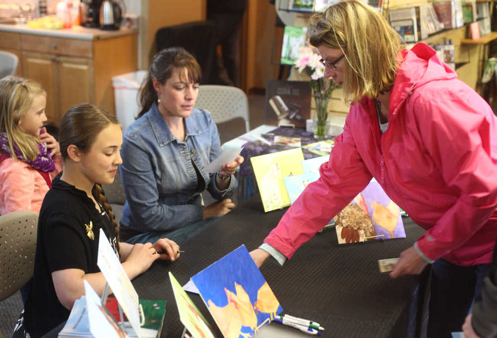 Photo by Kelly Sullivan/ Peninsula Clarion Whitney Owens sells a copy of Winston's Friendship Journey at her book signing Saturday, May 9. 2015, at King's Treasures in Kenai, Alaska.