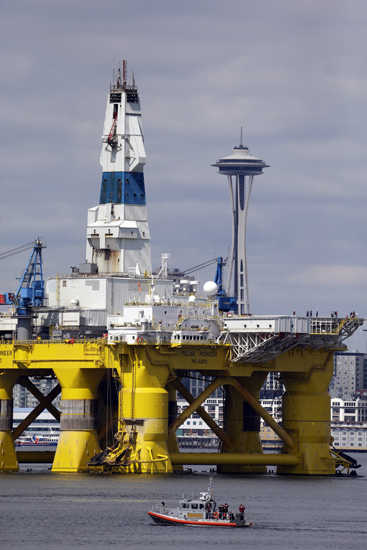The oil drilling rig Polar Pioneer is towed toward a dock and in view of the Space Needle Thursday, May 14, 2015, in Elliott Bay in Seattle. The rig is the first of two drilling rigs Royal Dutch Shell is outfitting for oil exploration and was towed to the Port of Seattle site despite the city's warning that it lacks permits and threats by kayaking environmentalists to paddle out in protest. (AP Photo/Elaine Thompson)