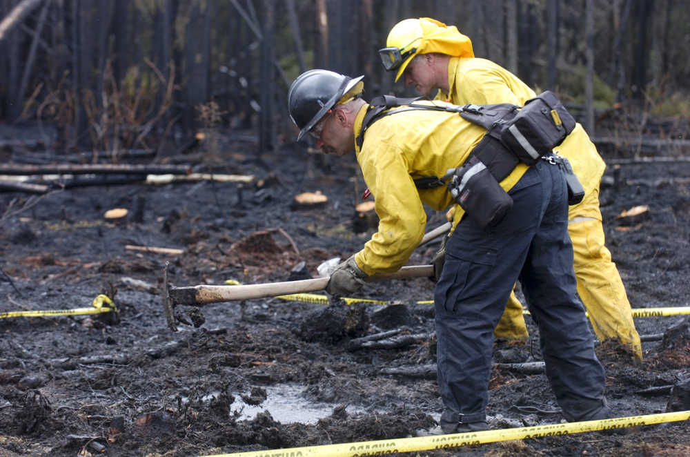 Photo by Rashah McChesney/Peninsula Clarion  A firefighter from the state Division of Forestry works to soak the ground after a half-acre wildfire burned along Robin Avenue on Sunday May 24, 2015 in Funny River, Alaska.