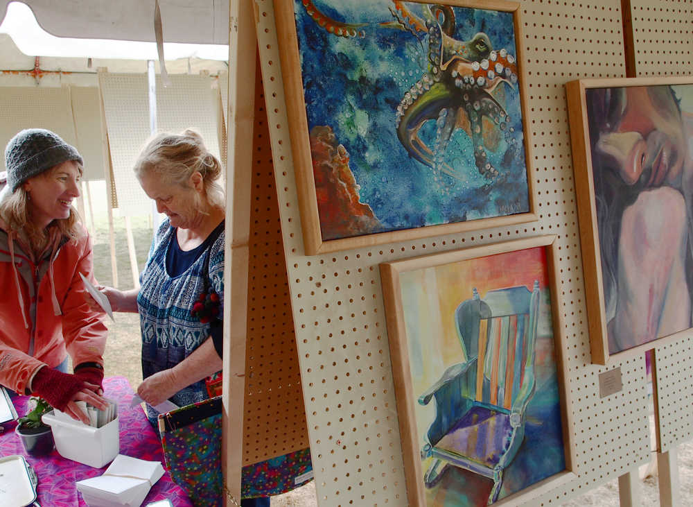 Ben Boettger/Peninsula Clarion Watercolor artist Francine Long (left) talks with a visitor, with paintings by Kaitlin Vadla in the foreground, during the Emerging Artists Festival on Saturday at Soldotna Creek Park in Soldotna.