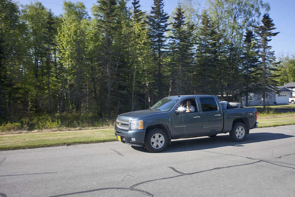 Photo by Rashah McChesney/Peninsula Clarion  A Soldotna man waves as he drives past a lot on Riverview Avenue on Thursday May 28, 2015, that the city council recently voted to sell to the owners of a neighboring home in Soldotna, Alaska.