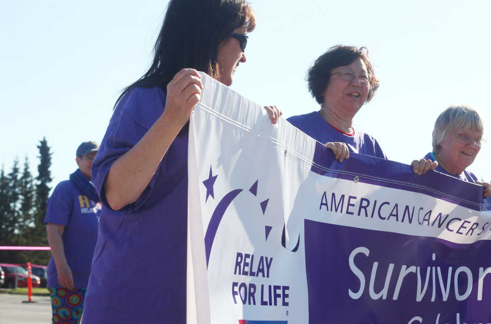 Photo by Kelly Sullivan/ Peninsula Clarion Linda Ruffridge, Romi Haseo and Janice Sadler hold the banner during the 2015 Relay For Life survivor's lap Friday, May 29, 2015, at the Soldotna Regional Sports Complex in Soldotna, Alaska.