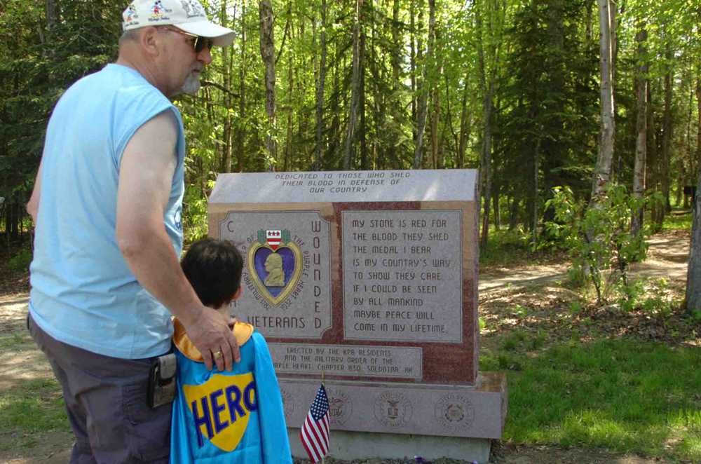 Ben Boettger/Peninsula Clarion Ron Lazenby and his caped grandson Koebryn Lazenby examine the memorial to wounded military veterans dedicated on Saturday by Soldotna's Chapter 830 of the Order of the Purple Heart in Soldotna Creek Park.