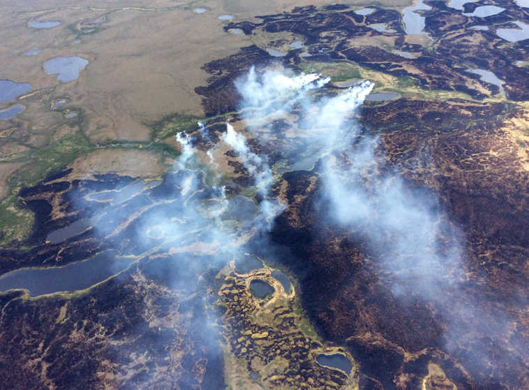 In this Sunday, June 7, 2015 photo, smoke rises from the Bogus Creek Fire, one of two fires burning in the Yukon Delta National Wildlife Refuge in southwest Alaska. Fire managers said Monday that weekend rain helped tamp down the fires which, together, total about 63 square miles. (Matt Snyder/Alaska Division of Forestry via AP)