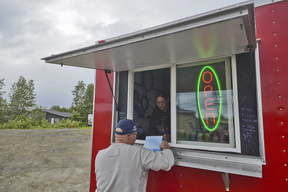 Photo by Rashah McChesney/Peninsula Clarion  Josh Bynum orders a burger from Harlene Bartlett on Tuesday June 9, 2015 at the Blue Moon Burgers mobile food stand on North Aspen Drive in Soldotna, Alaska. The city council will review several changes in the city's mobile food vendor regulations during its Wednesday meeting.