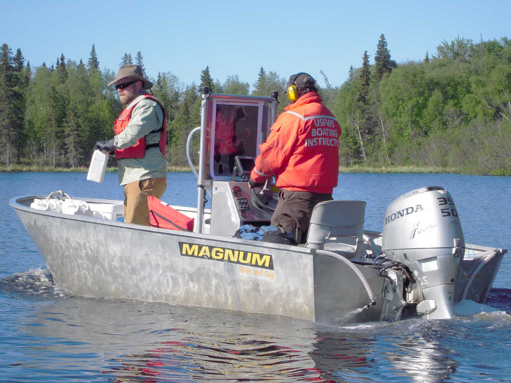 John Morton/Kenai Wildlife Refuge Andrew Skibo (left) of chemical manufacturer SePRO oversees application of the herbicide Diquat at Daniels Lake, in a boat piloted by Kenai Wildlife Refuge Biologist Todd Eskelin (right) on Tuesday, June 3 2014. After being mixed with lake water, liquid Diquat enters the lake from a spray-hose on the rear of the boat.